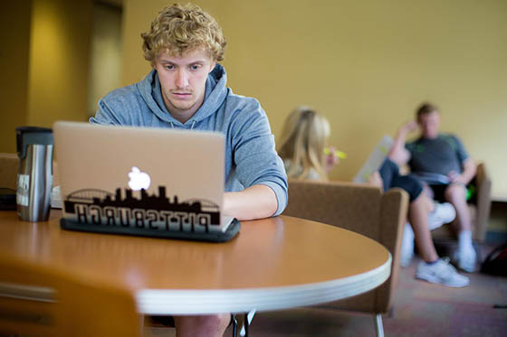 A student works at a table on his laptop